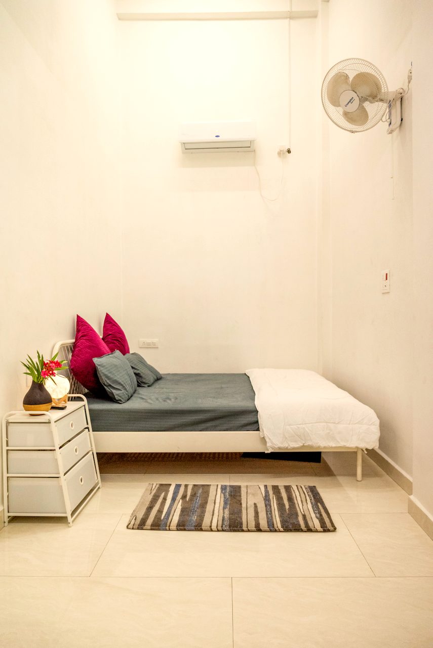The Premium room: a wide platform bed with magenta cushions, side chests and a striped runner on marble floor
